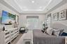 Lovely primary bedroom with custom window treatments and wood like tile flooring throughout.