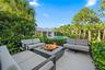 Expansive outdoor patio with a built-in fire pit, surrounded by lush landscaping and mature trees