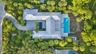 Modern architecture with a metal roof, two exterior pools, extensive landscaping, and a curvilinear paver driveway
