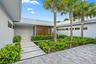 Paver driveway, mature palm trees, contemporary exterior, metal roof, and lush landscaping