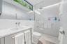 Modern bathroom featuring a vanity with an integrated sink, polished chrome wall-mounted faucet, a flush-mounted toilet, and a glass-enclosed shower w