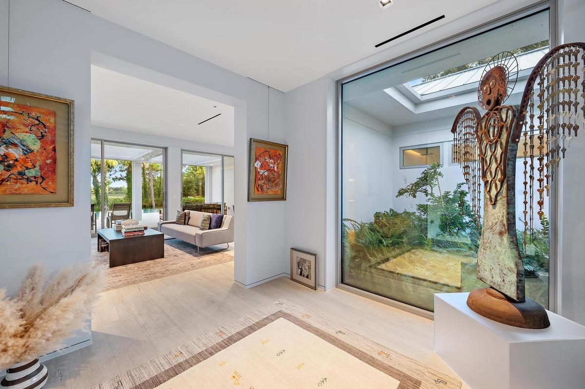 Bright, open interior showcasing light wood-finish flooring, recessed ceiling lighting, and large glass sliding doors framing landscape views
