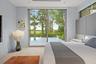 Expansive sliding glass doors, light wood-finish flooring, recessed ceiling lighting, and a built-in upholstered headboard
