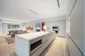 Open-concept kitchen with a large island featuring a built-in microwave, integrated appliances, and light wood-finish flooring