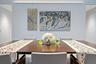 Wood-finish dining table with upholstered chairs, recessed lighting, and wall-mounted art display system