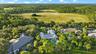 Aerial view showcasing a striking contemporary residence nestled on expansive grounds surrounded by mature landscaping and native vegetation