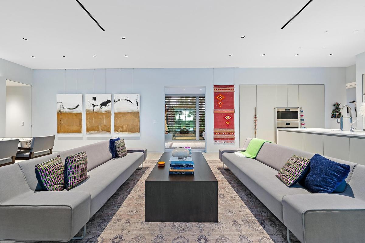 Open-concept living space with recessed lighting and a sleek kitchen featuring integrated appliances and an island with a sink