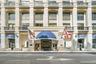 Multi-story facade featuring arched windows, Juliet balconies with wrought iron railings, and a grand entrance with a blue awning