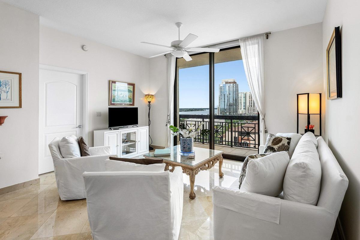 Expansive glass sliding doors open to a balcony with metal railings, offering city and Intracoastal views
