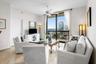 Expansive glass sliding doors open to a balcony with metal railings, offering city and Intracoastal views