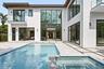 Open interior featuring large-format tile flooring, frameless glass panel railings, floor-to-ceiling black-framed windows, and recessed lighting