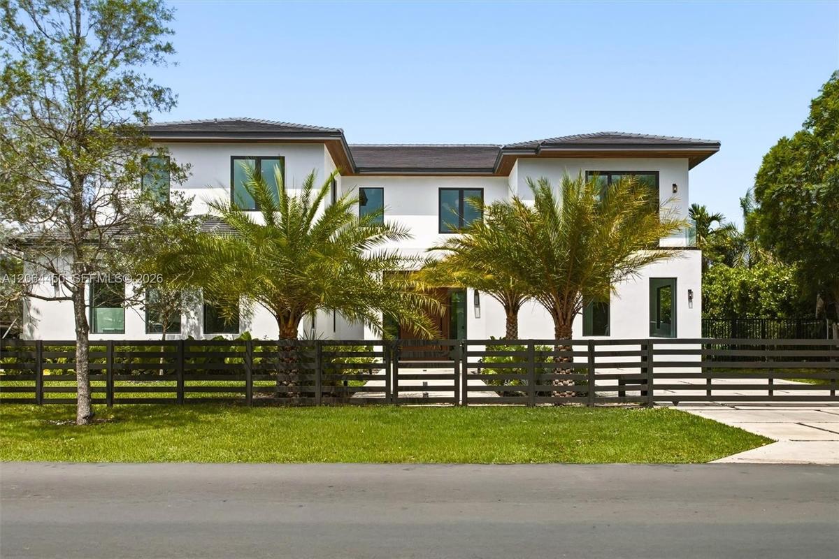 Modern two story residence framed by mature royal palms and manicured landscaping