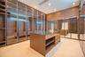 Open-concept room featuring floor-to-ceiling multi-panel glass doors, wood-finish cabinetry, neutral large-format tile flooring, and recessed lighting