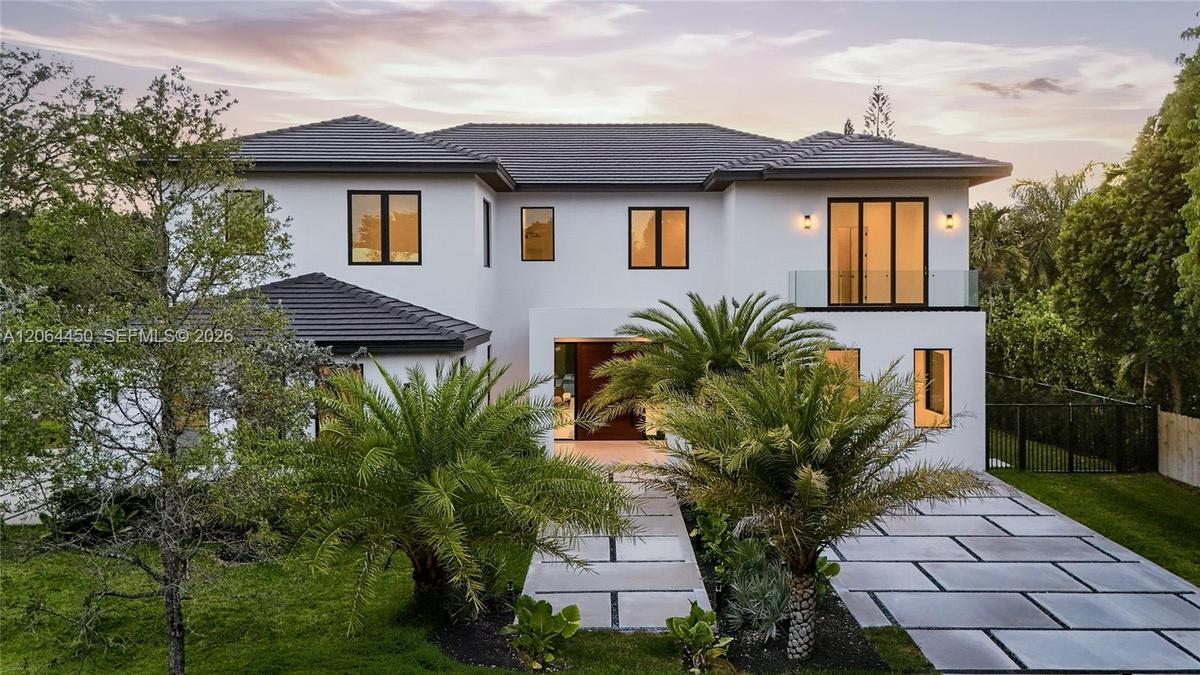 Modern exterior featuring white stucco finish, wood-grain entry door, dark-framed vertical windows, and architectural wall-mounted lighting