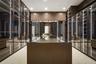 Open-concept interior featuring large-format stone flooring, floor-to-ceiling glass sliding doors, built-in floor-to-ceiling cabinetry, and a kitchen 