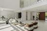 Great room with floor to ceiling windows framing the pool and tropical landscaping