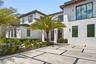 Two-story modern exterior featuring a smooth white stucco finish, dark-framed windows, a flat tile roof, and a horizontal privacy fence