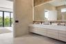 Living area featuring floor-to-ceiling glass sliding doors, recessed tray ceiling, large-format tile flooring, and wall-mounted floating cabinetry