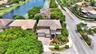 Stucco exterior featuring a two-story turret, arched entryway, decorative molding, concrete driveway, and mature landscaping