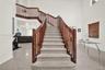 Two-story interior featuring high ceilings, neutral tile flooring, arched windows, and a wooden staircase railing
