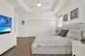 Room featuring wood-finish flooring, vaulted ceiling, arched window with a transom, and bifold closet doors