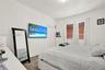 Tray ceiling with integrated lighting, wood-finish flooring, ceiling fan, and built-in wall niche