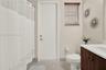 Neutral-toned tile flooring, large window with a deep sill, and dual-panel closet doors featuring white millwork, complete with a mounted ceiling fan 