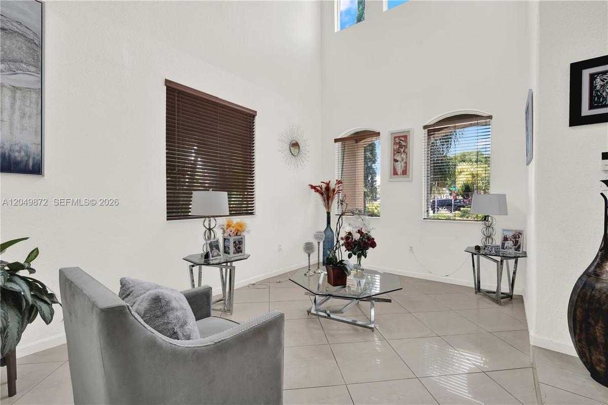 Kitchen featuring natural wood-finish cabinetry, solid-surface countertops, and a stainless steel French-door refrigerator, complemented by tile floor