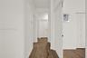 Hallway featuring wood-finish flooring, a built-in recessed wall niche, and a wooden handrail with vertical balusters