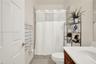 Bathroom featuring a wood-finish vanity with a solid-surface countertop, an expansive wall-mounted mirror, a tiled shower enclosure, and a built-in so