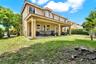 Two-story residence featuring a stucco exterior, a covered rear patio with concrete flooring, and an expansive lawn