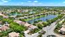 Aerial perspective featuring a two-story residence with a concrete tile roof, paved driveway, multi-car garage, and waterfront positioning