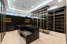 Extraordinary glass-enclosed boutique wardrobe with illuminated cabinetry, custom display cases, extensive storage, and a central dressing island with