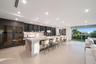 Showpiece 20-foot illuminated onyx bar featuring generous seating, custom smoked-glass cabinetry, dual wine storage, and sweeping skyline views.