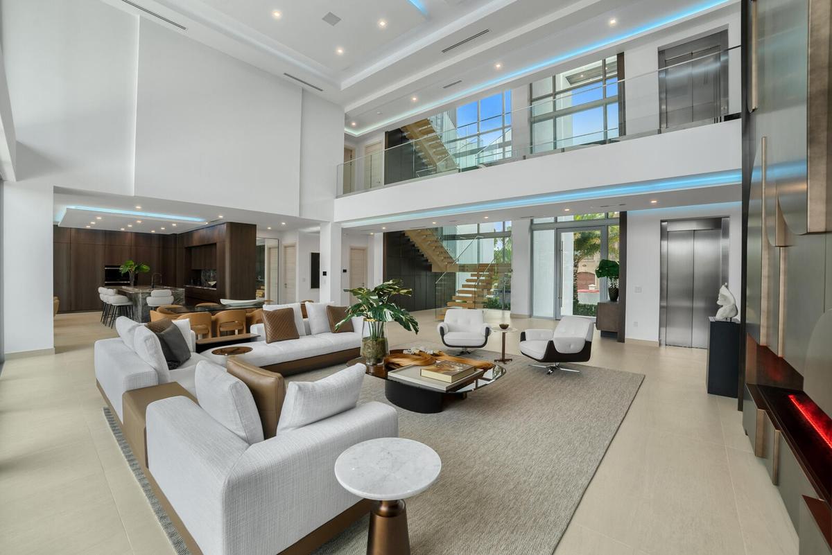 Grand interior perspective showcasing the floating wood staircase, frameless glass railings, commercial-grade elevator, and customizable architectural