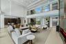 Grand interior perspective showcasing the floating wood staircase, frameless glass railings, commercial-grade elevator, and customizable architectural