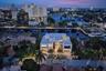 A breathtaking twilight aerial showcases the residence’s illuminated modern architecture, tropical landscaping, and exceptional waterfront setting, fr