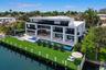 Spectacular waterfront setting featuring a 75-foot infinity-edge pool with integrated spa and submerged sun shelf, a covered summer kitchen and barbec