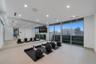 Glass-enclosed fitness studio featuring a mirrored wall, dedicated workout space, and direct access to the turf terrace with elevated city views.