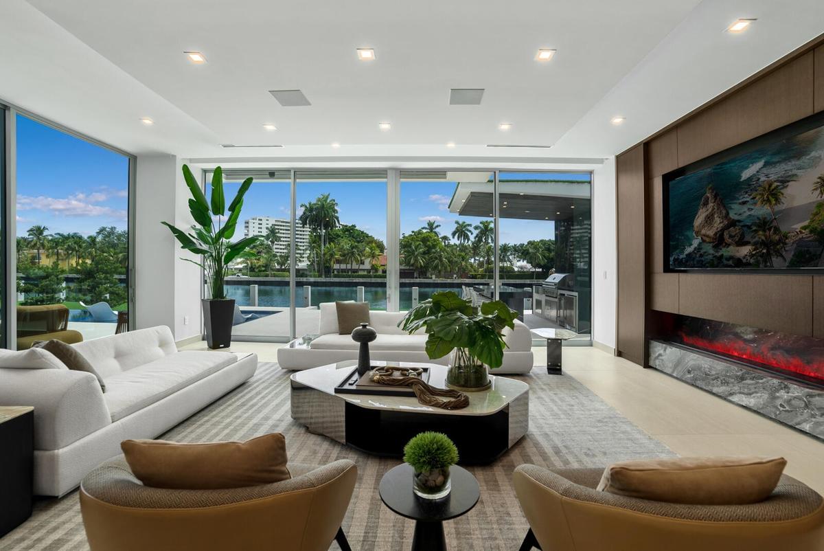 Waterfront family and TV room with custom millwork, a built-in television, linear fireplace with dramatic natural-stone surround, and floor-to-ceiling