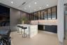 VIP suite’s full private bar showcasing a luminous waterfall-edge stone counter, seating for three, sink, wine refrigeration, illuminated backsplash, 