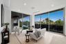 Waterfront sitting area within the primary suite, surrounded by walls of glass and opening directly to the private covered terrace.