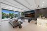 Expansive VIP lounge with floor-to-ceiling glass, serene waterfront views, custom wall paneling, oversized television, and direct access to the outdoo