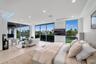 Private primary retreat with floor-to-ceiling glass framing sweeping canal and skyline views from the bedroom and adjoining sitting area.