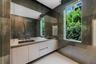 Luxurious en-suite bath finished with floor-to-ceiling stone, a floating dual-sink vanity, an oversized mirror, frameless glass shower, and abundant n