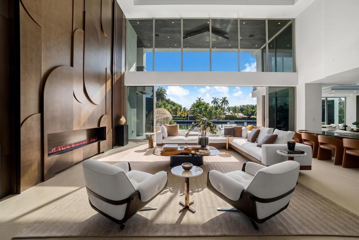 Sun-filled waterfront great room featuring floor-to-ceiling glass, refined designer furnishings, and seamless views of the pool and canal.