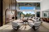 Sun-filled waterfront great room featuring floor-to-ceiling glass, refined designer furnishings, and seamless views of the pool and canal.