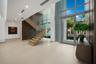 Dramatic first-floor entry showcasing soaring ceilings, a striking wood-paneled feature wall, and a floating staircase with glass railings.