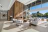 Soaring two-story great room framed by floor-to-ceiling glass, a dramatic paneled feature wall, linear fireplace, and captivating waterfront views.