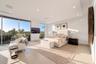 Serene second-floor primary bedroom featuring a private waterfront sitting area, walls of glass, and direct access to the covered terrace.
